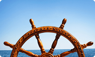 A wooden steering wheel on the ocean.