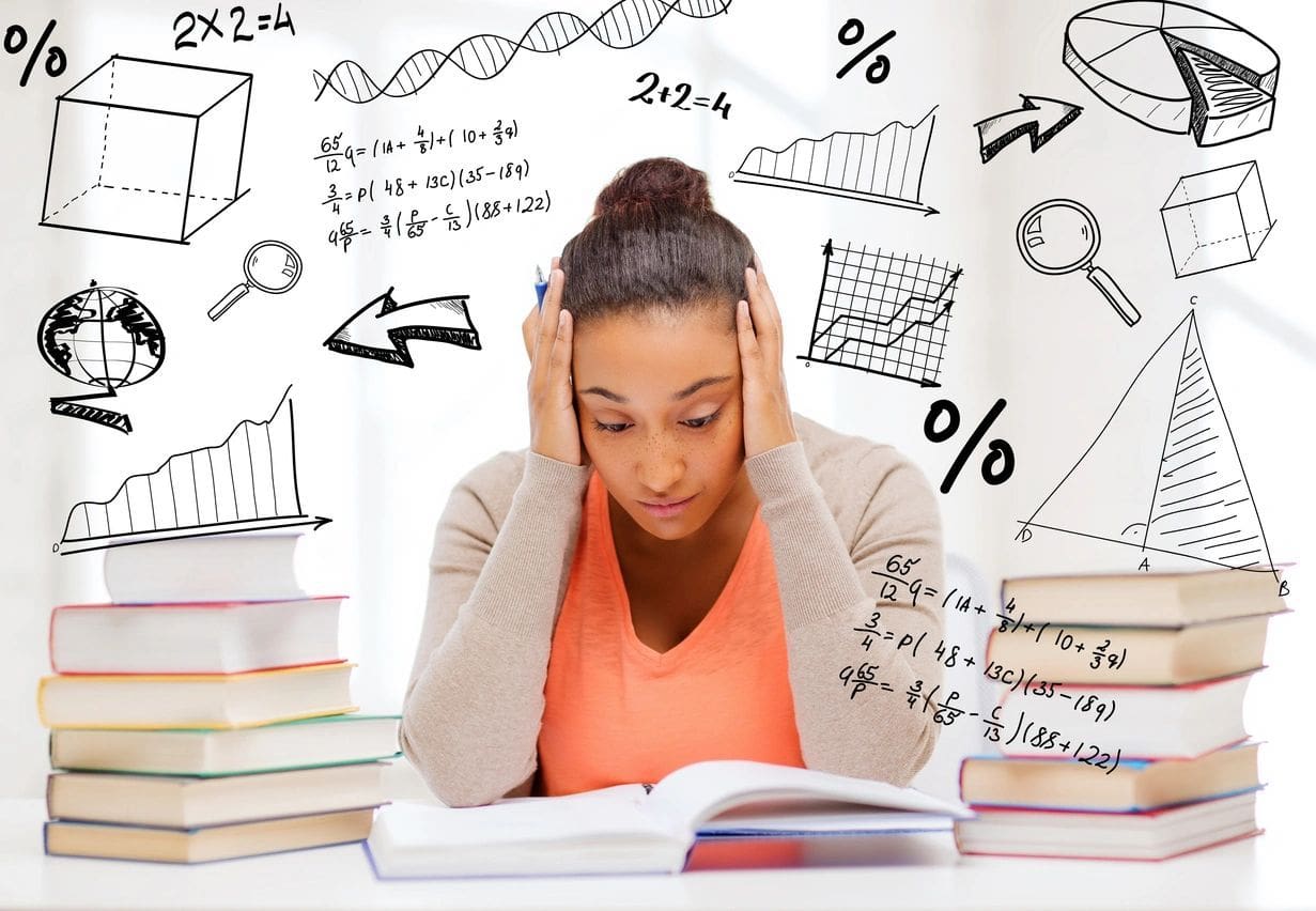 A girl is sitting at her desk with books and papers.